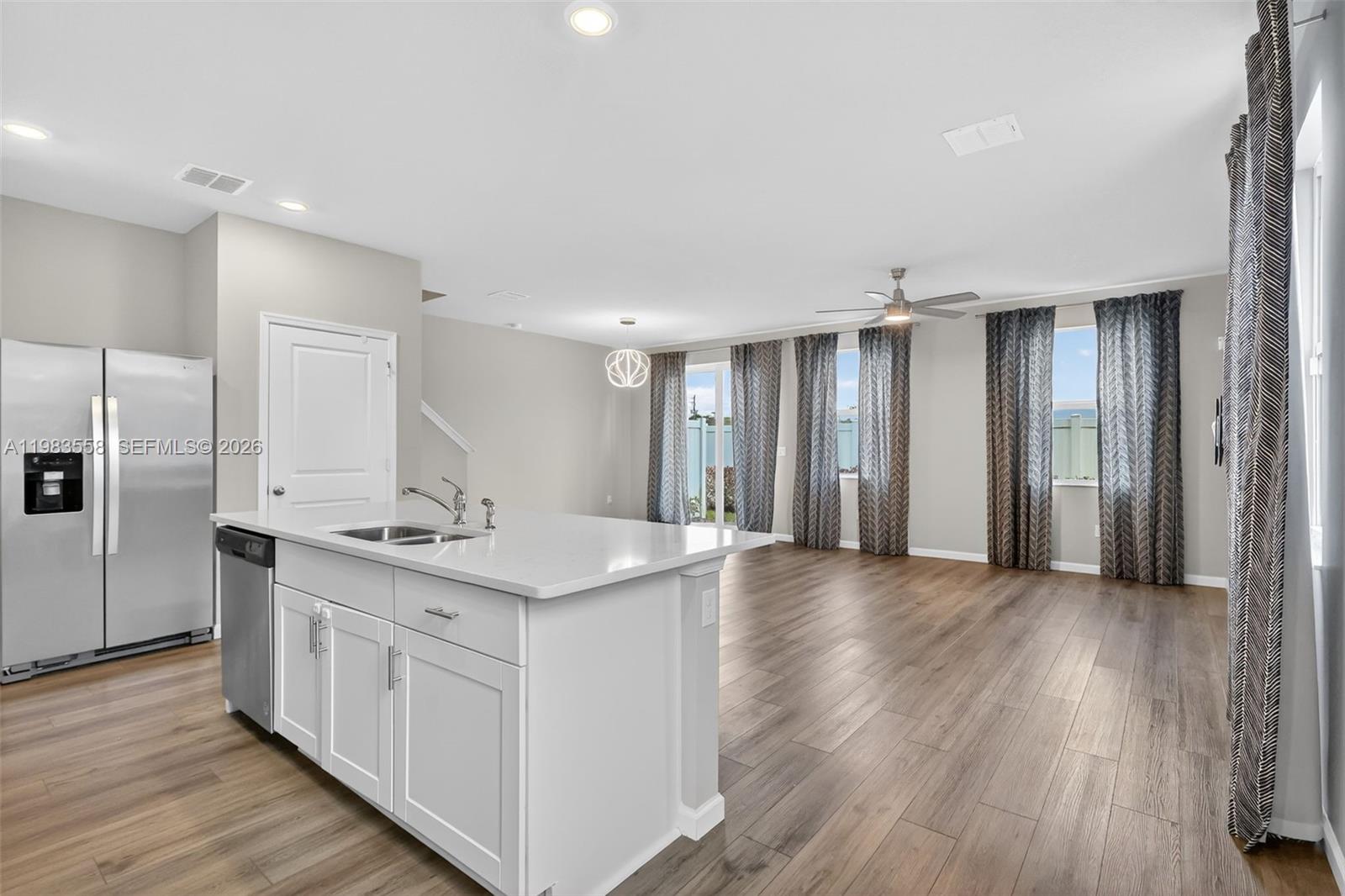 A kitchen with a white island and stainless steel appliances opens into a living area — 5610 SE Edgewater Cir, Stuart FL 34997, STUART, FL