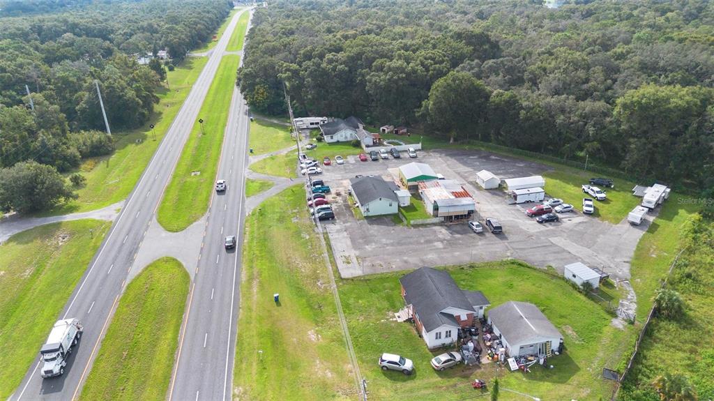An aerial view shows a commercial property with multiple buildings and parking lots beside a highway — 2480 N WOODLAND BOULEVARD, DELAND, FL
