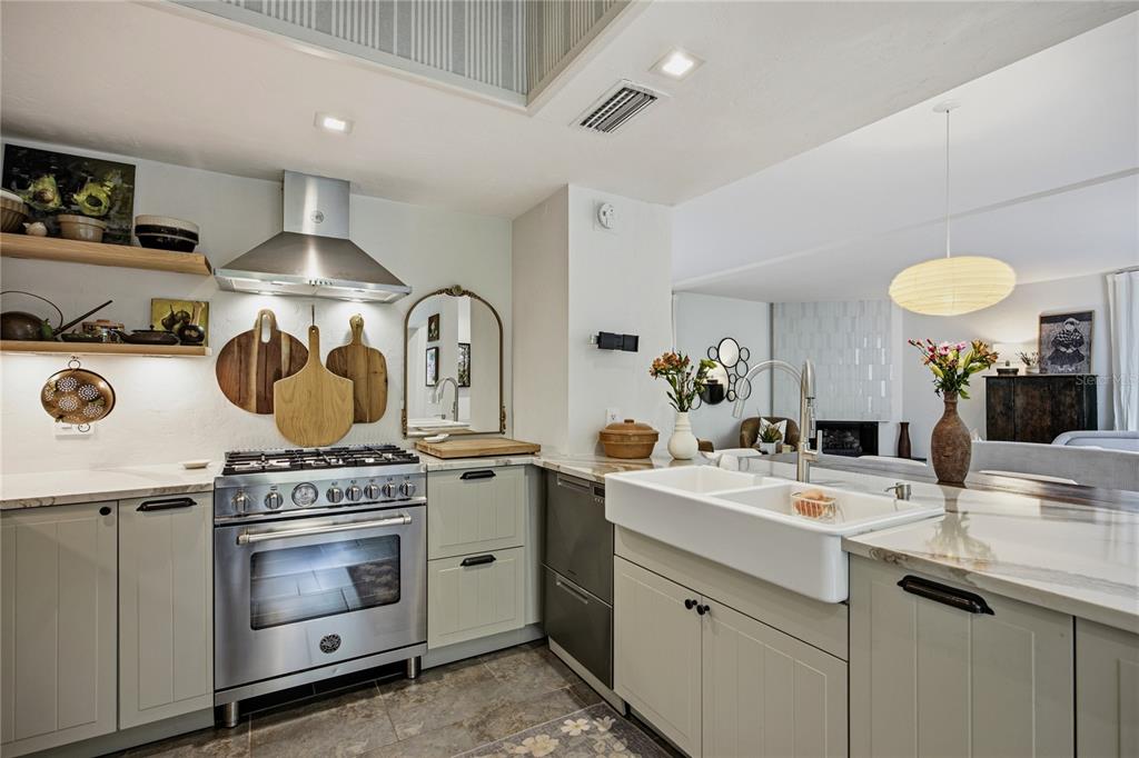 A kitchen features light green cabinetry, a farmhouse sink, stainless steel appliances, and open shelving — 2012 NW 24TH STREET, GAINESVILLE, FL