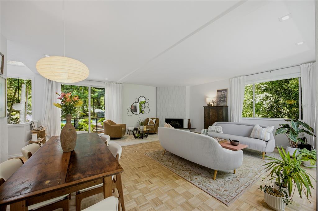 An open-concept living and dining room features parquet wood floors, a fireplace, and large windows — 2012 NW 24TH STREET, GAINESVILLE, FL