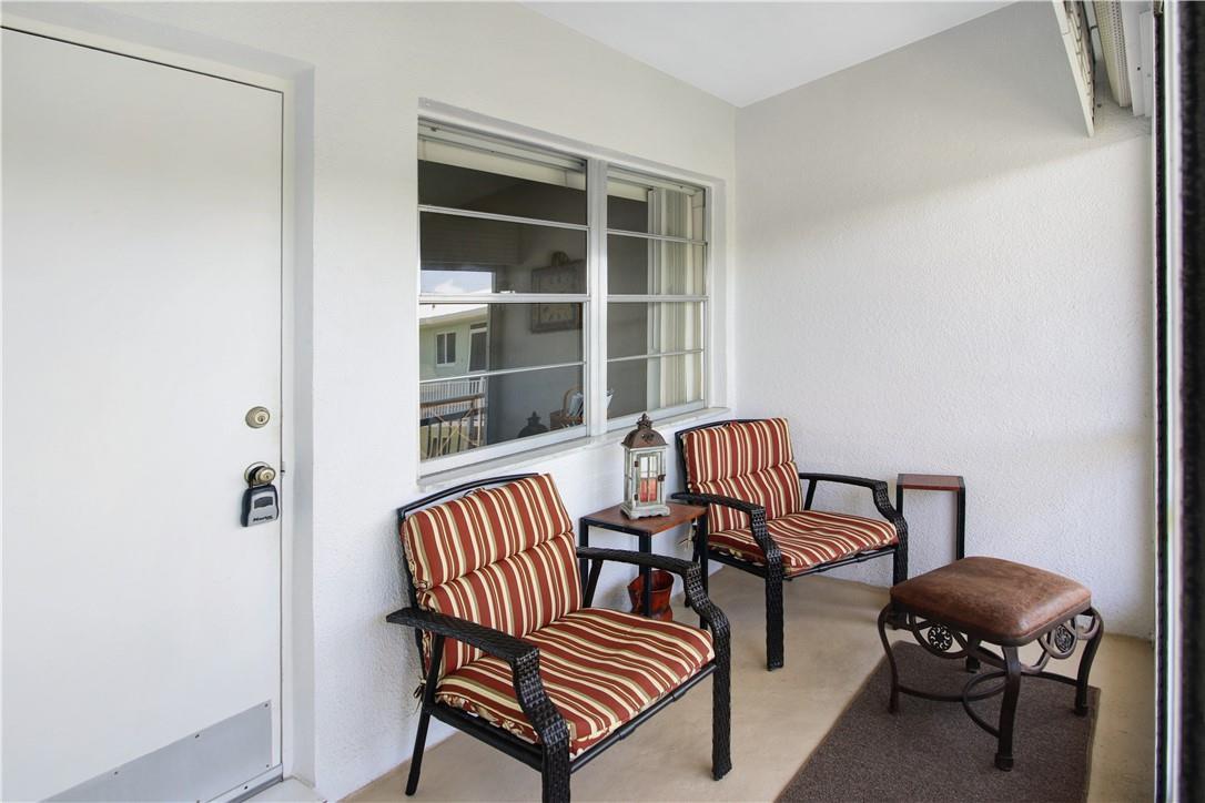 A covered patio features two striped chairs, a small side table, and a brown ottoman — 2100 NE 38th Street # 222, Lighthouse Point FL 33064, LIGHTHOUSE POINT, FL