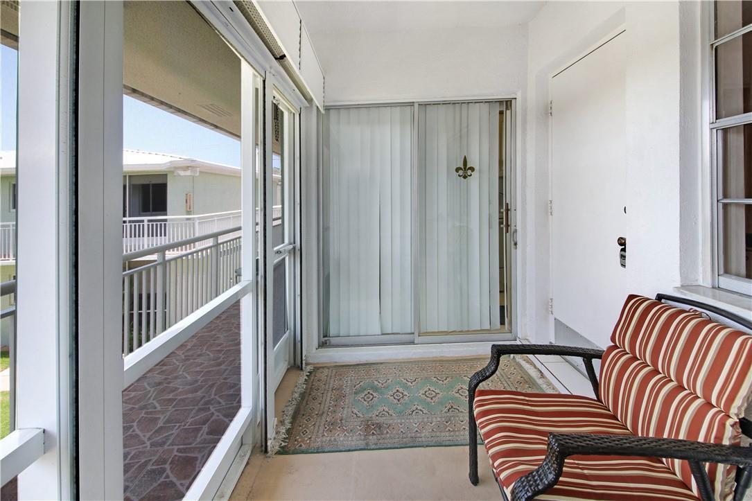 A screened-in balcony features a striped chair, a patterned rug, and sliding glass doors — 2100 NE 38th Street # 222, Lighthouse Point FL 33064, LIGHTHOUSE POINT, FL