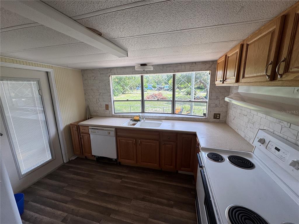 A kitchen features wood cabinets, white appliances, a large window, and wood-look flooring — 11351 S ANN POINT, HOMOSASSA, FL