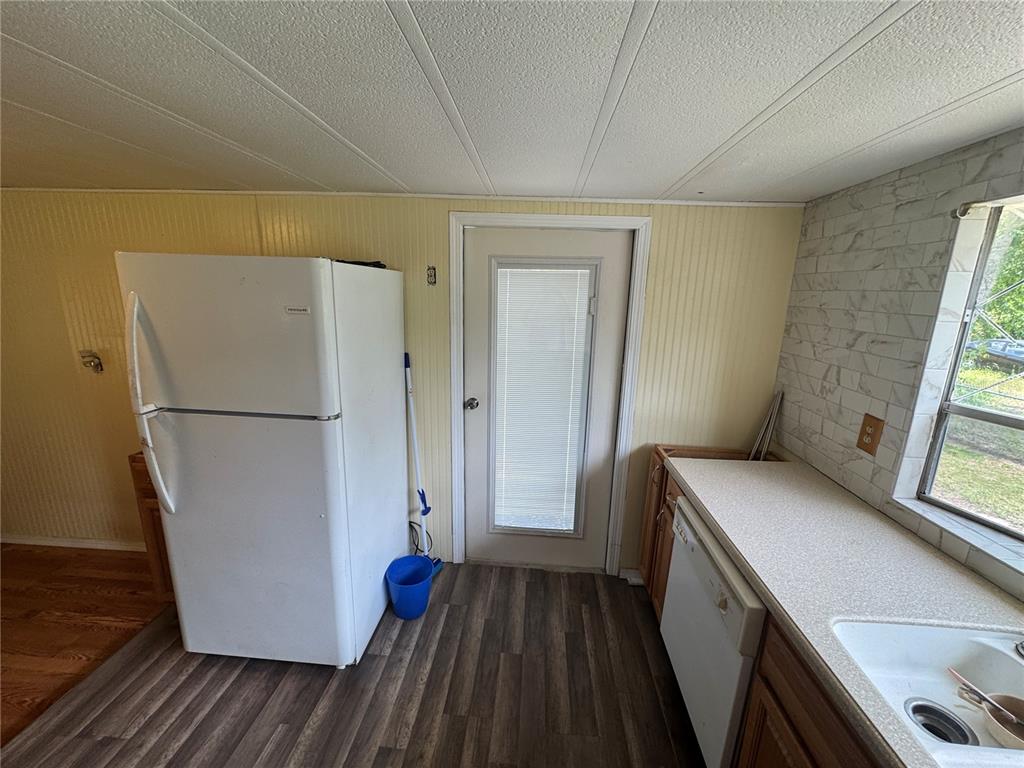 A kitchen features a white refrigerator, a dishwasher, a glass-paneled door, and wood-look flooring — 11351 S ANN POINT, HOMOSASSA, FL