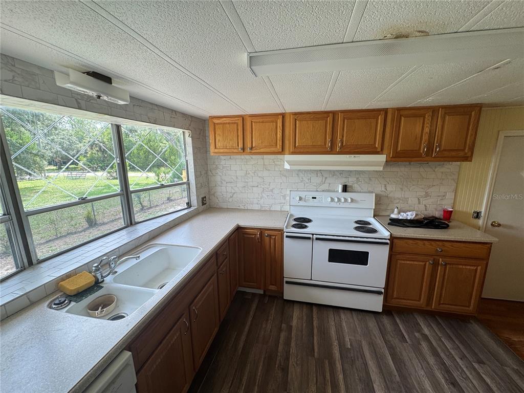 A kitchen features wood cabinets, a white stove, a double sink, and a tiled backsplash — 11351 S ANN POINT, HOMOSASSA, FL
