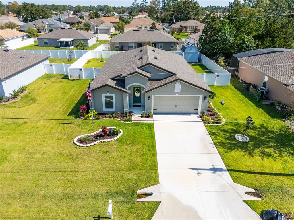An aerial view shows a single-story house with a gray exterior, two-car garage, and lawn — 35 ROLLINS LANE, PALM COAST, FL