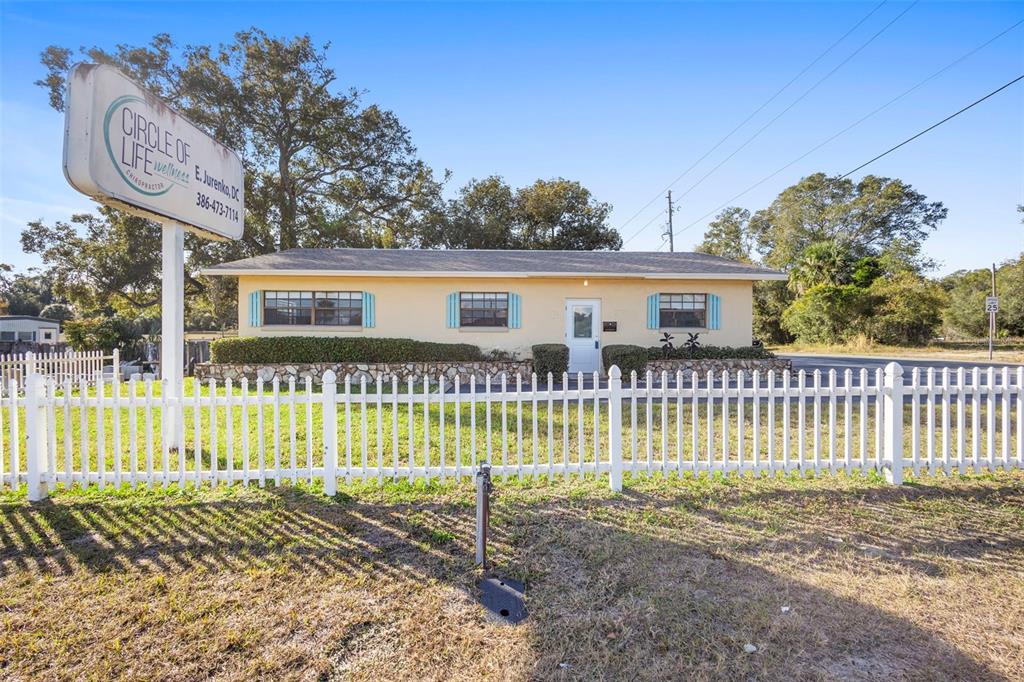 A single-story yellow building with a white picket fence and a chiropractic sign — 1995 N VOLUSIA AVENUE, ORANGE CITY, FL