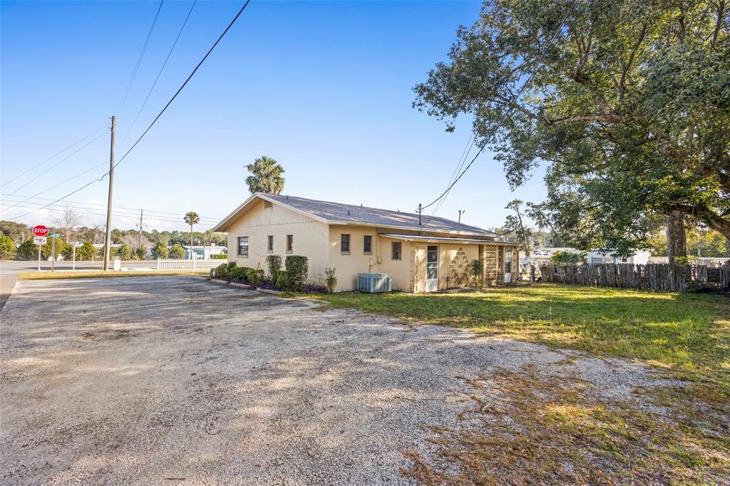 A single-story beige building with a gravel parking lot and a large tree nearby — 1995 N VOLUSIA AVENUE, ORANGE CITY, FL