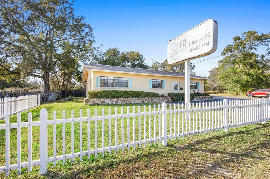 A yellow single-story building with a white picket fence and a prominent sign — 1995 N VOLUSIA AVENUE, ORANGE CITY, FL