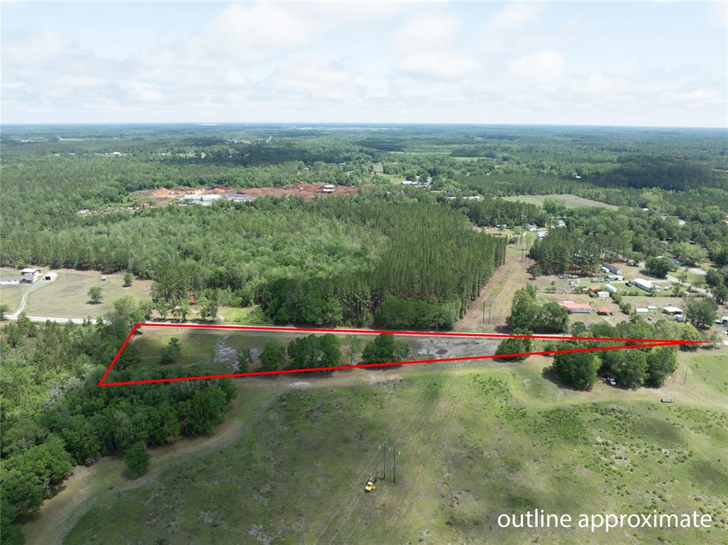 An aerial view shows a triangular plot of land outlined in red near trees — NW 185TH STREET, STARKE, FL