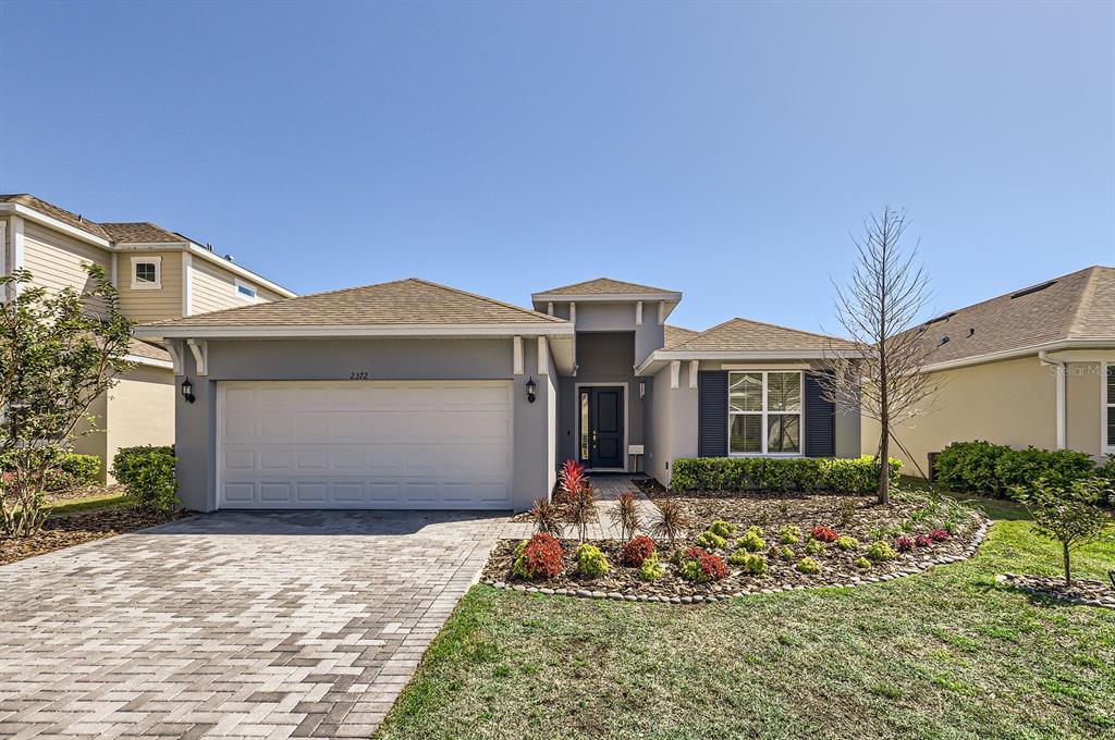 A single-story house with a gray exterior, a two-car garage, and a landscaped front yard — 2372 SIRENA LANE, MOUNT DORA, FL