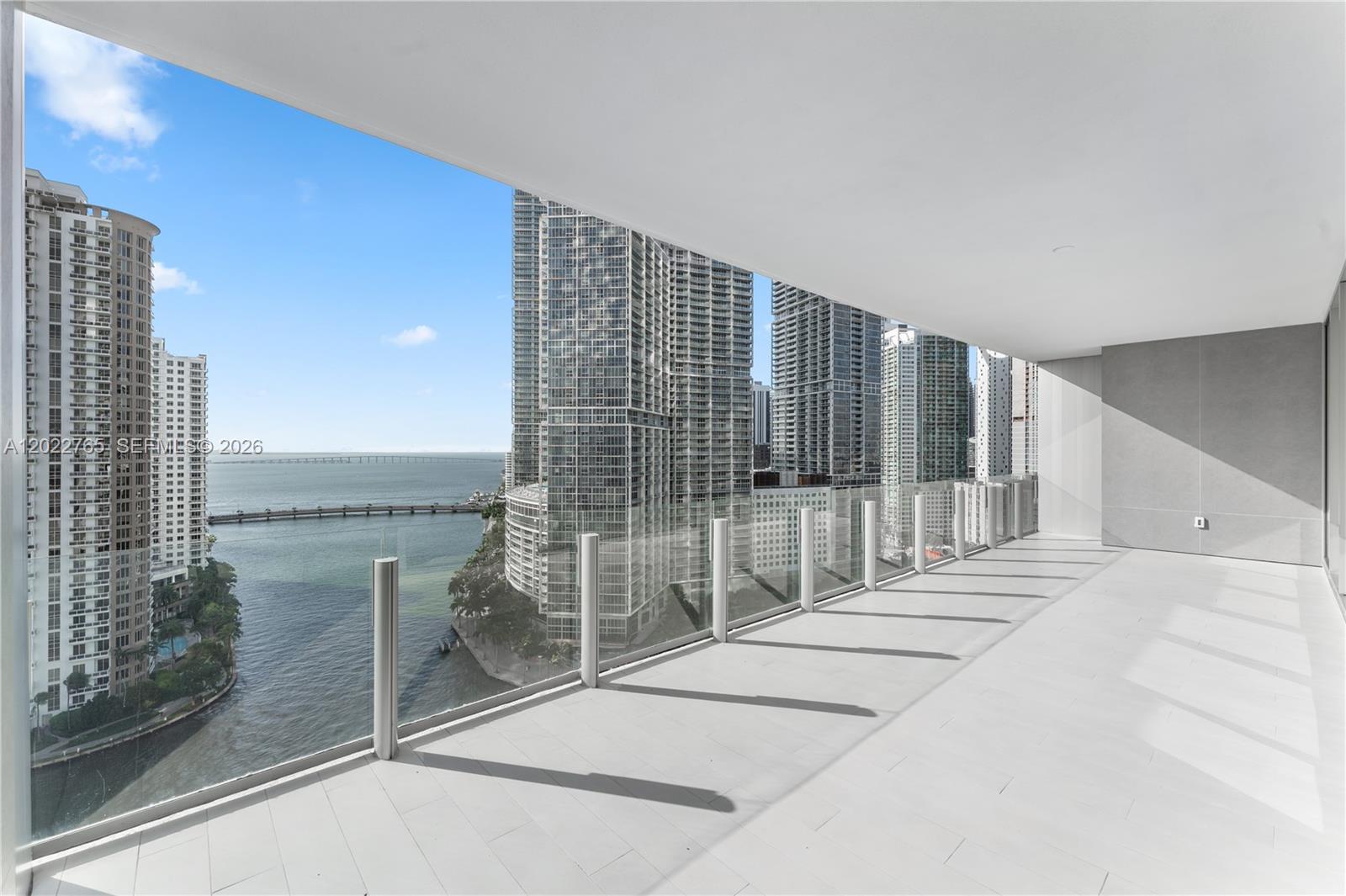 A modern balcony features light-colored tile flooring, a glass railing, and views of city skyscrapers — 300 Biscayne Blvd Way # 1802, Miami FL 33131, MIAMI, FL