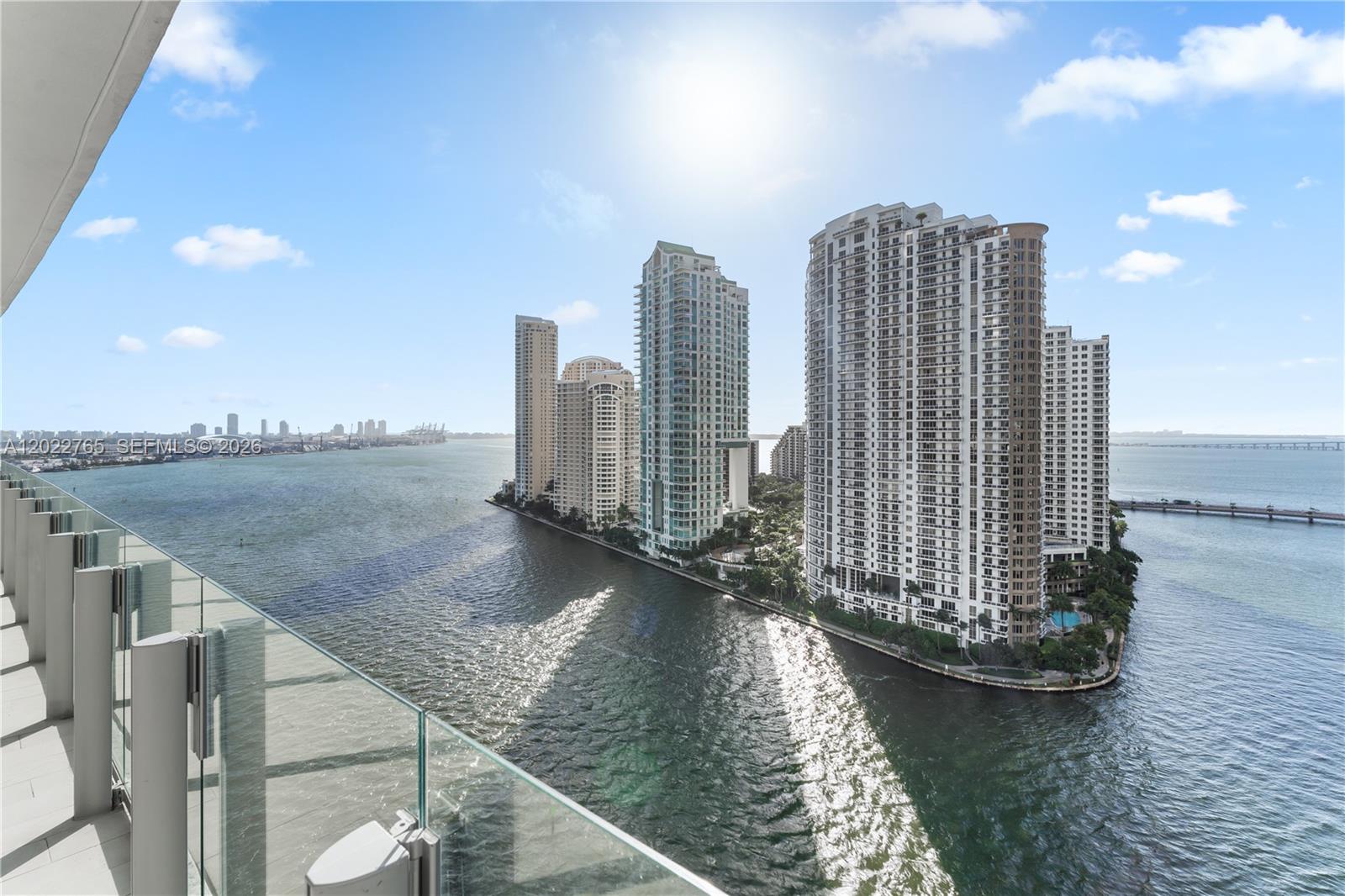 A balcony view overlooks a narrow peninsula with several high-rise residential buildings surrounded by water — 300 Biscayne Blvd Way # 1802, Miami FL 33131, MIAMI, FL