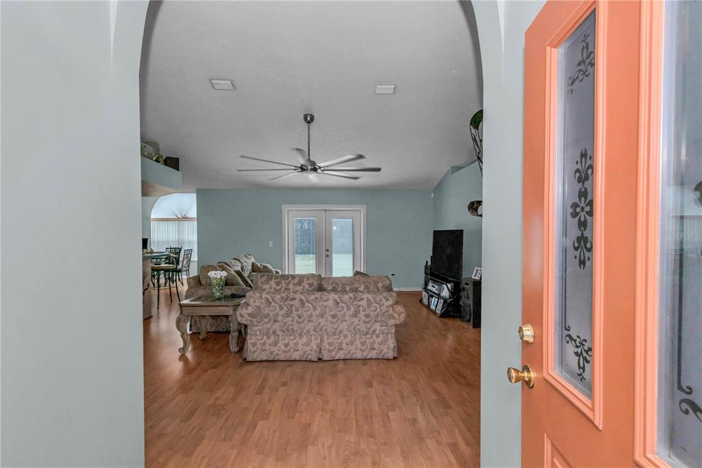 A view from an orange front door into a living room with light wood flooring — 14147 SW 33 CT ROAD, OCALA, FL