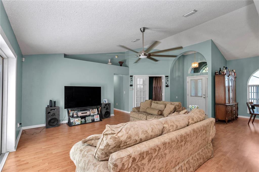 A living room features light blue walls, wood-look flooring, a ceiling fan, and patterned furniture — 14147 SW 33 CT ROAD, OCALA, FL