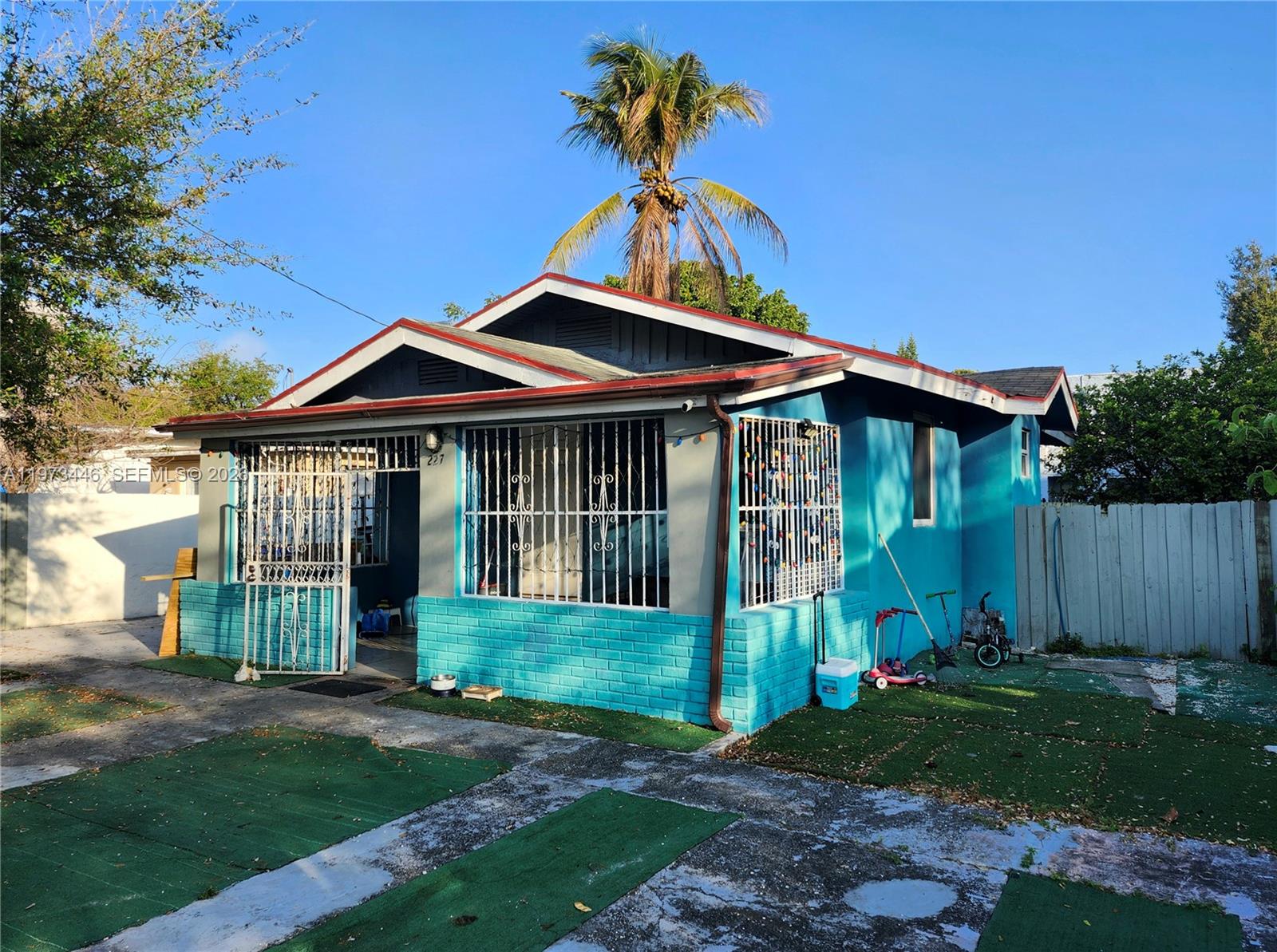A blue single-story house with a white security gate and metal window bars — 227 NW 33rd St, Miami FL 33127, MIAMI, FL