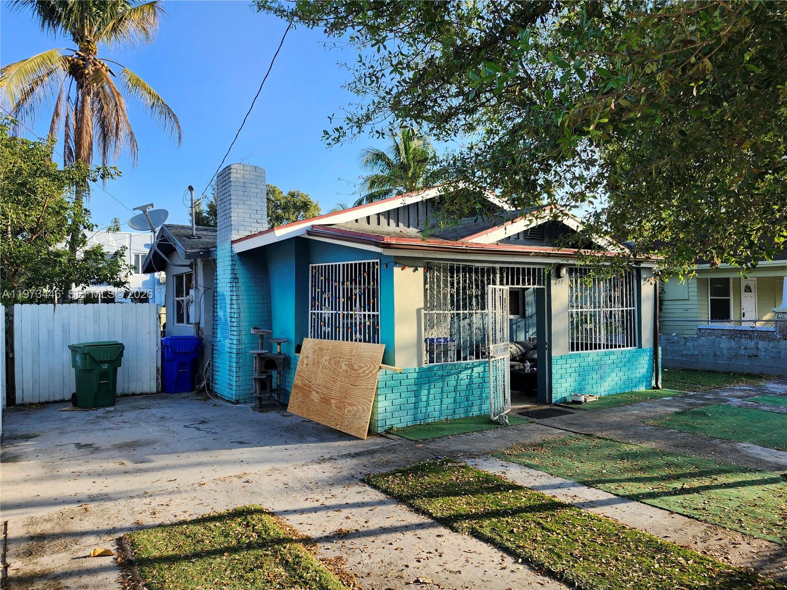A single-story house with a blue brick chimney and exterior, security bars, and a driveway — 227 NW 33rd St, Miami FL 33127, MIAMI, FL