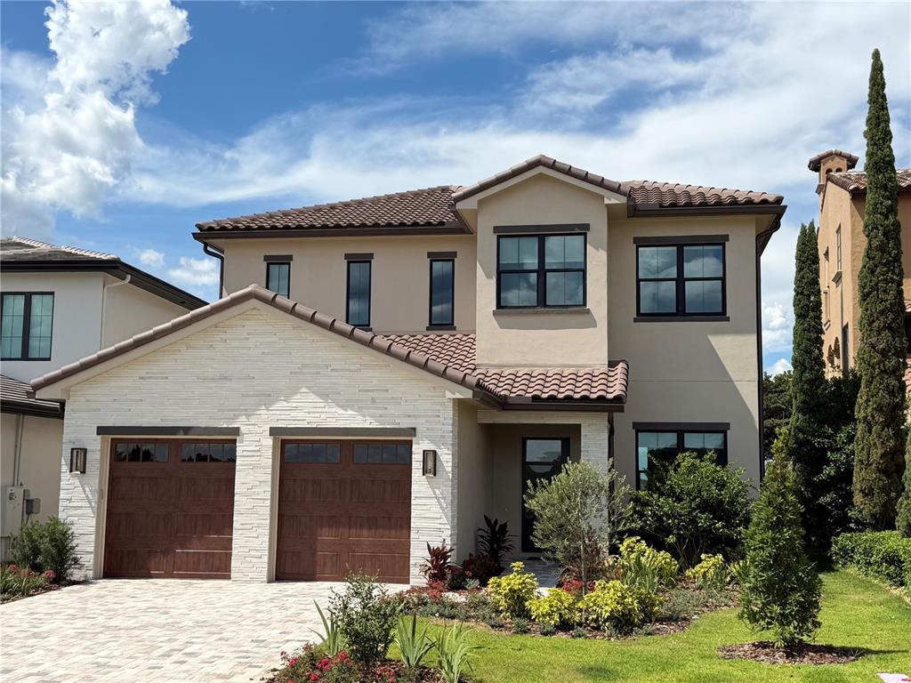 A two-story house with a stone-veneer garage, tile roof, and a paved driveway — 15915 VETTA DRIVE, MONTVERDE, FL