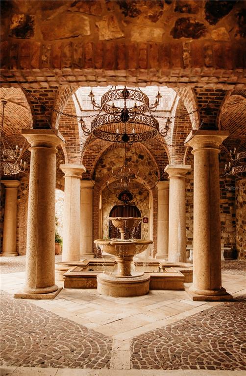 A stone courtyard features a central tiered fountain, arched brick ceilings, and large stone columns — 15915 VETTA DRIVE, MONTVERDE, FL