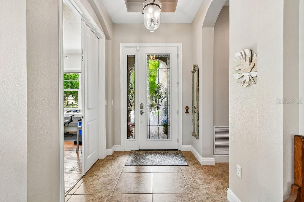 A bright entryway features a glass-paneled front door, tile flooring, and a recessed ceiling light — 112 SUFFOLK COURT, DELAND, FL