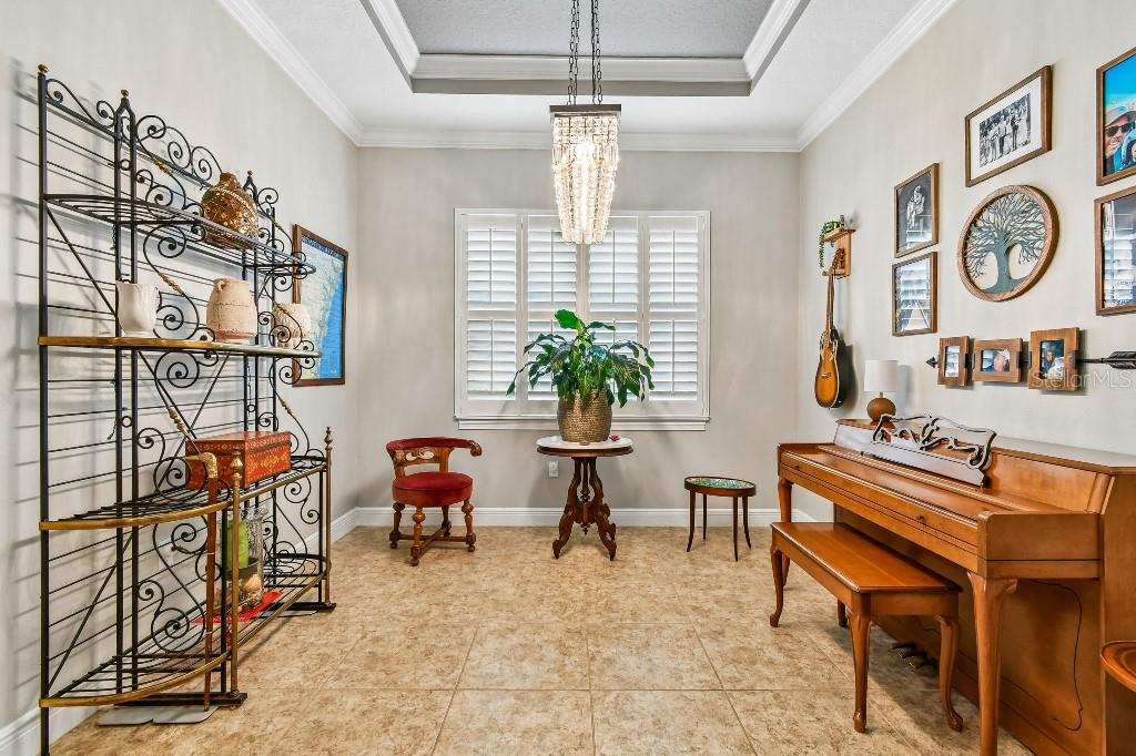 A room with tile flooring, a piano, a metal shelving unit, and a crystal chandelier — 112 SUFFOLK COURT, DELAND, FL