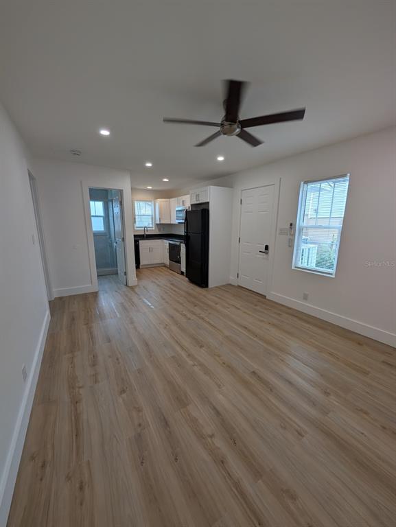 A kitchen and living area with light wood-look flooring, white cabinets, and a ceiling fan — 1834 28TH AVENUE N, ST PETERSBURG, FL