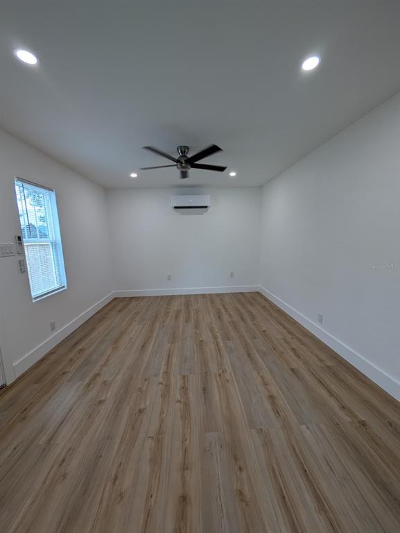 An empty room features light wood-look flooring, white walls, a ceiling fan, and a mini-split — 1834 28TH AVENUE N, ST PETERSBURG, FL