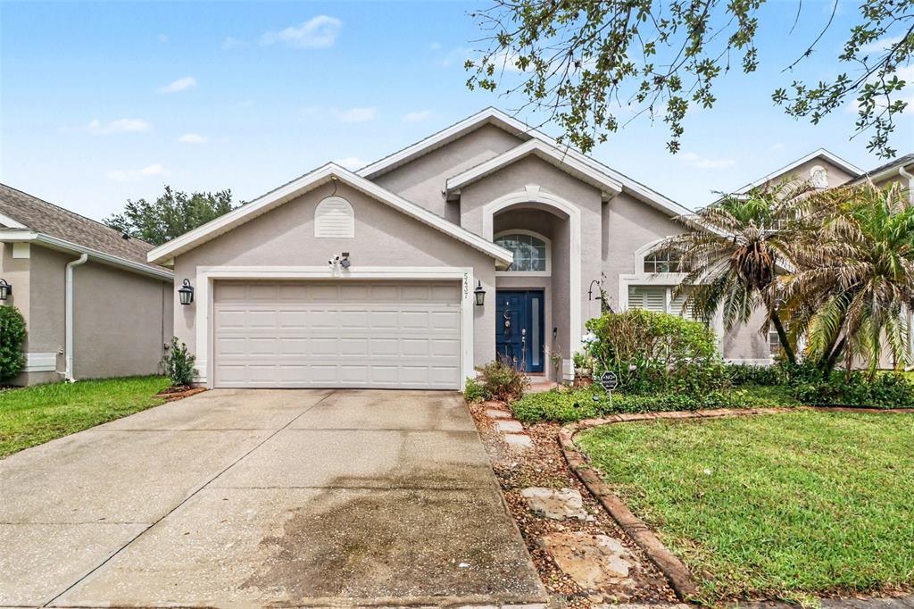 A single-story house with a beige stucco exterior, a two-car garage, and a blue front door — 5437 FLORENCE HARBOR DRIVE, ORLANDO, FL