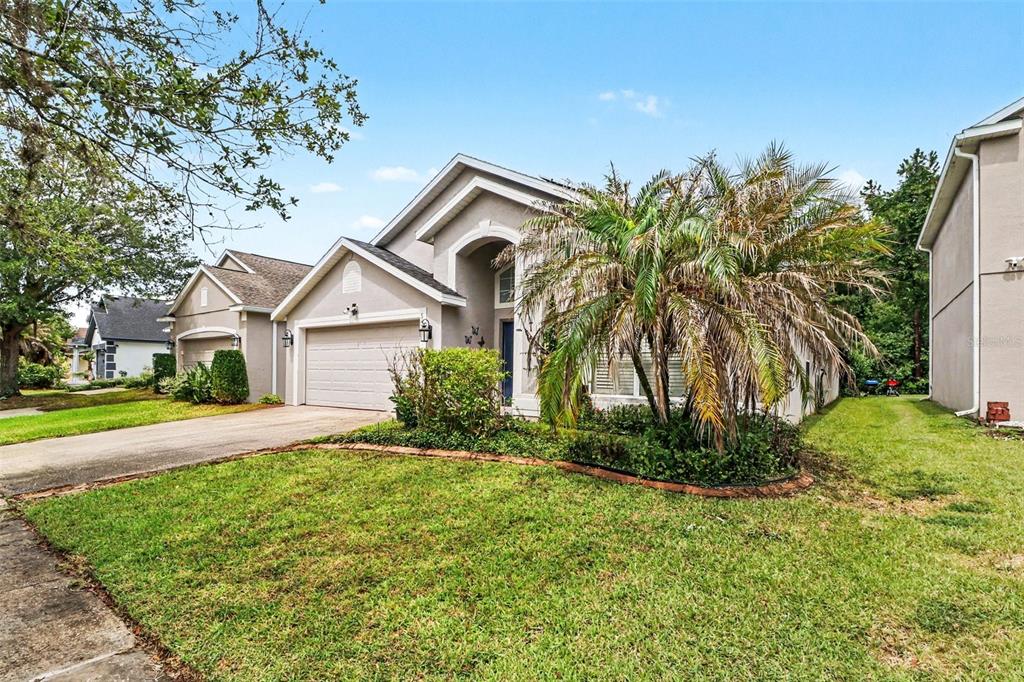 A beige suburban house with a two-car garage and a large palm tree in front — 5437 FLORENCE HARBOR DRIVE, ORLANDO, FL