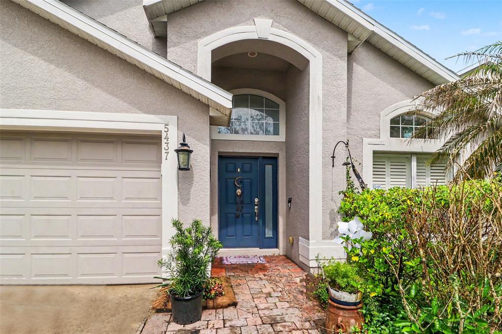 A house exterior features a blue front door, a brick walkway, and a garage — 5437 FLORENCE HARBOR DRIVE, ORLANDO, FL