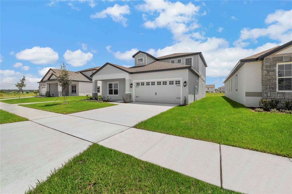 A two-story suburban house with a white garage and a green lawn under a sky — 3348 CHINOTTO DRIVE, LAKE ALFRED, FL