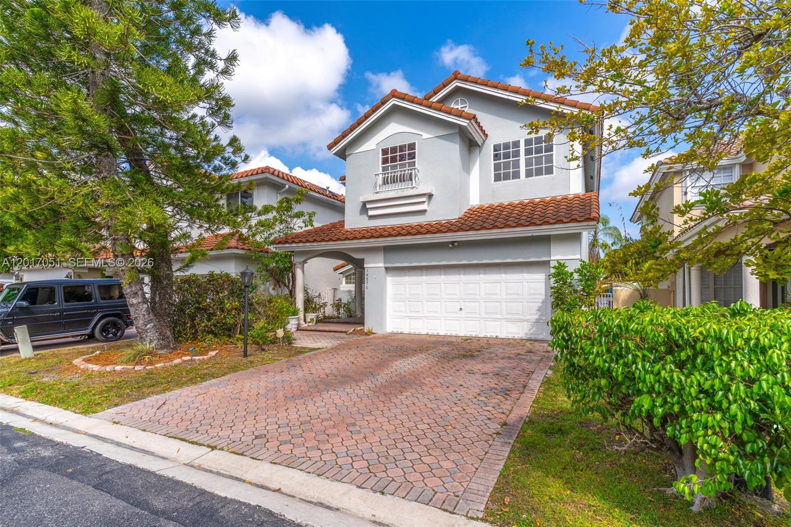 A two-story house with a brick driveway, a white garage door, and a tiled roof — 14876 SW 132nd Ave, Miami FL 33186, MIAMI, FL
