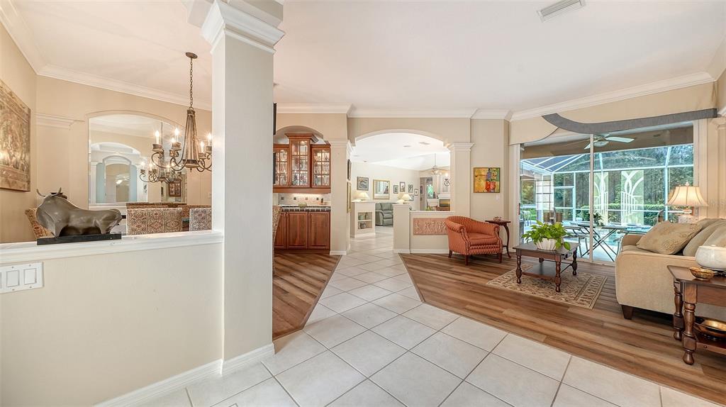 A bright open-concept living area features tile and wood flooring, arched transitions, and a patio view — 4727 CARRINGTON CIRCLE, SARASOTA, FL