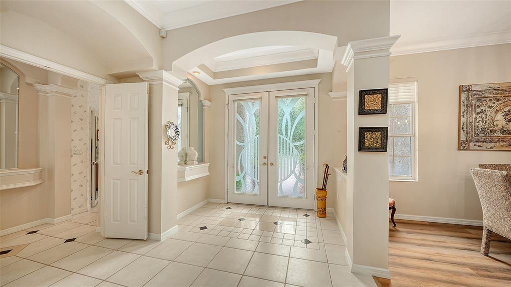 A bright entryway features white tile floors, double glass-paneled doors, and an arched ceiling — 4727 CARRINGTON CIRCLE, SARASOTA, FL