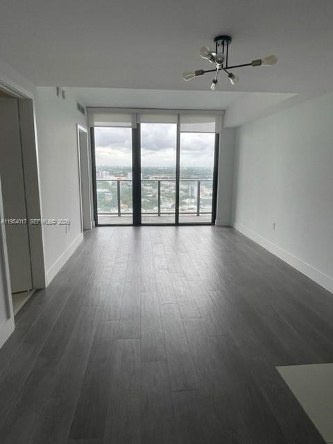 An empty room with gray wood-look flooring, a modern light fixture, and floor-to-ceiling windows — 121 NE 34th St # 2110, Miami FL 33137, MIAMI, FL
