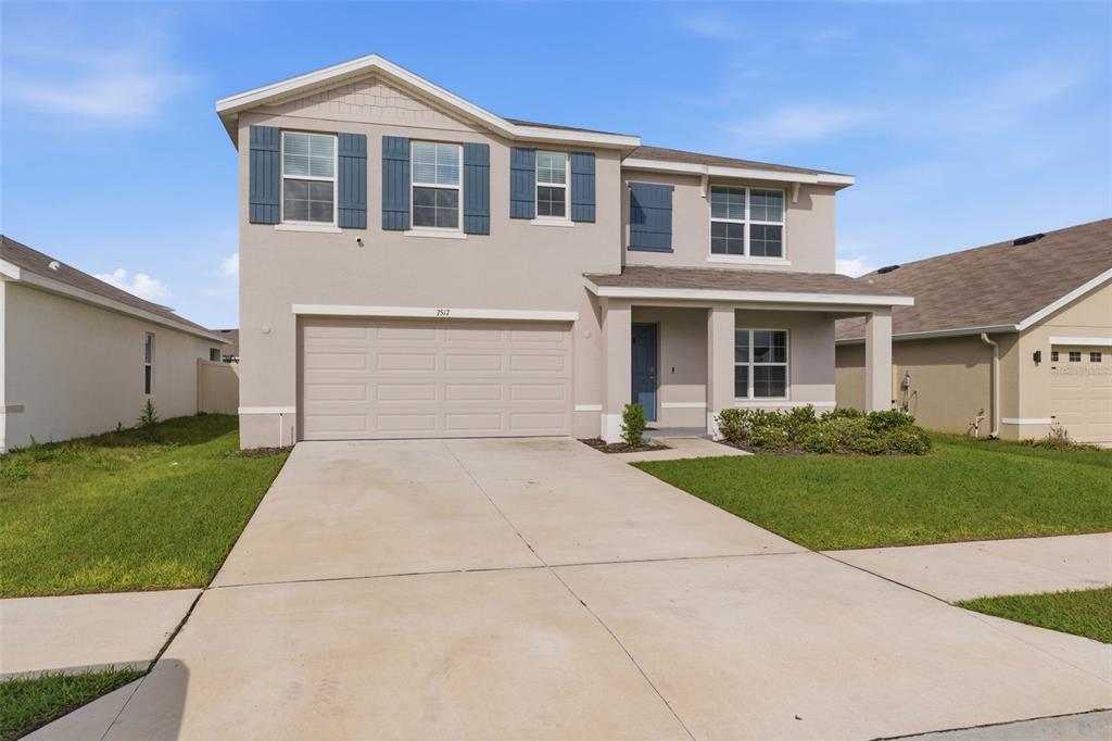 A two-story suburban house features a beige stucco exterior, a two-car garage, and blue shutters — 7517 GARDNER STREET, BROOKSVILLE, FL