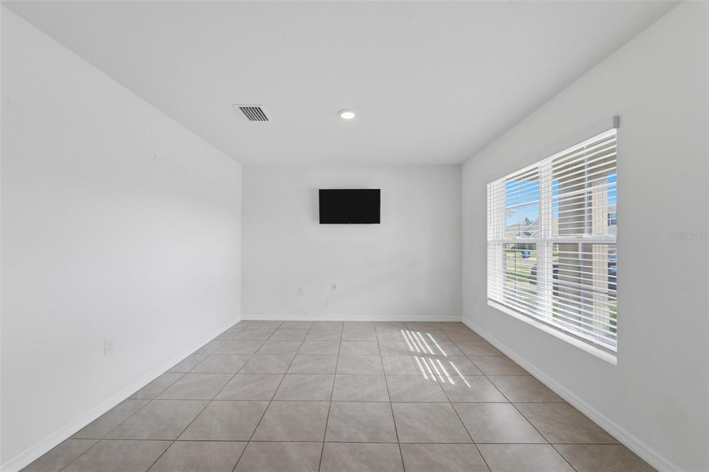 An empty room with light-colored tile flooring, white walls, and a window with blinds — 7517 GARDNER STREET, BROOKSVILLE, FL