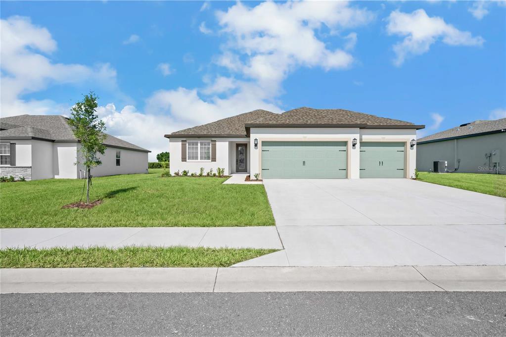 A single-story house with a light-colored exterior, two garage doors, and a concrete driveway — 640 TANGELO TERRACE, BABSON PARK, FL