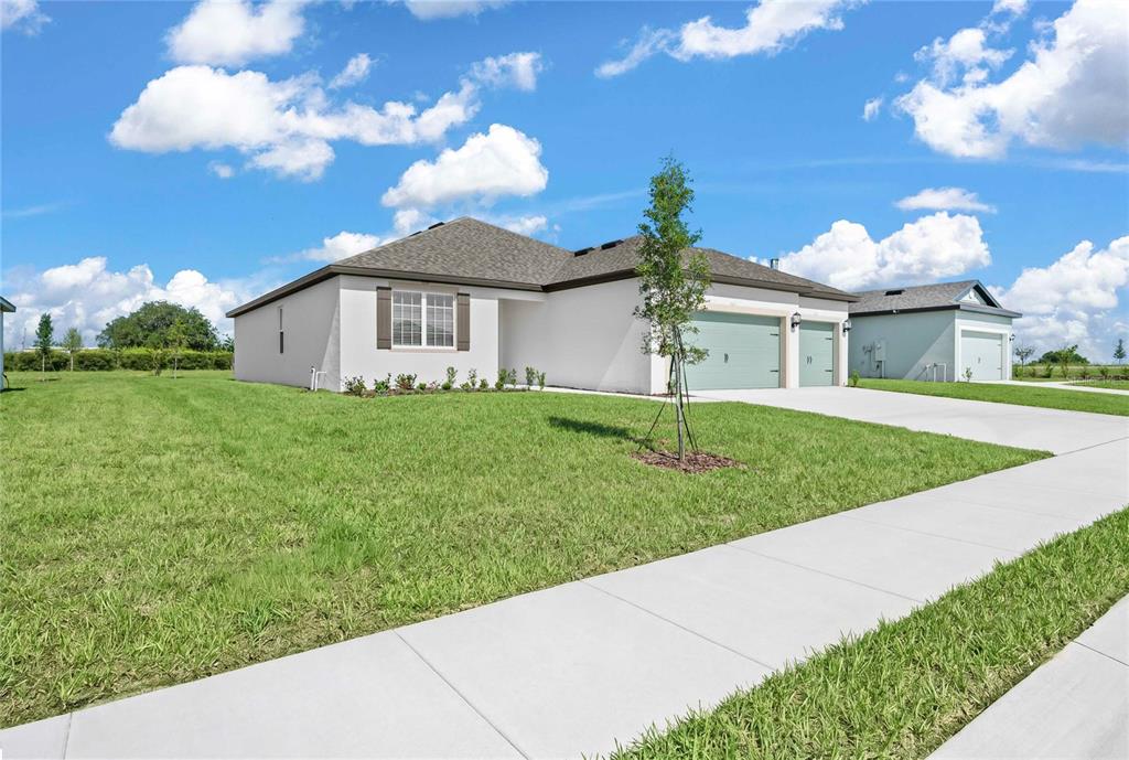 A single-story house with a white exterior, a two-car garage, and a large front lawn — 640 TANGELO TERRACE, BABSON PARK, FL