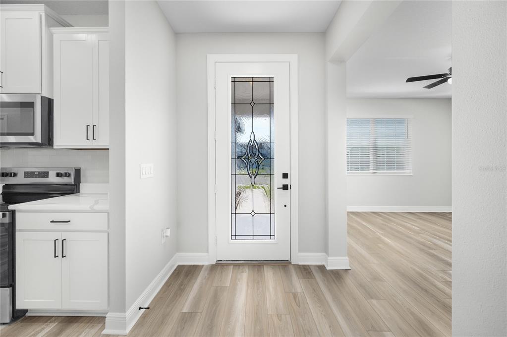 A white front door with a decorative glass insert sits between a kitchen and living area — 640 TANGELO TERRACE, BABSON PARK, FL