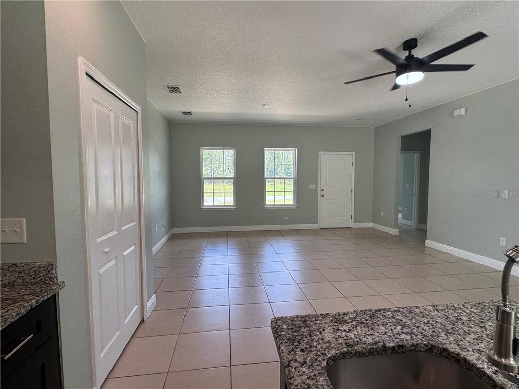 An open-concept living area features light-colored tile flooring, a ceiling fan, and two windows — 6839 SW 149TH LANE ROAD, OCALA, FL