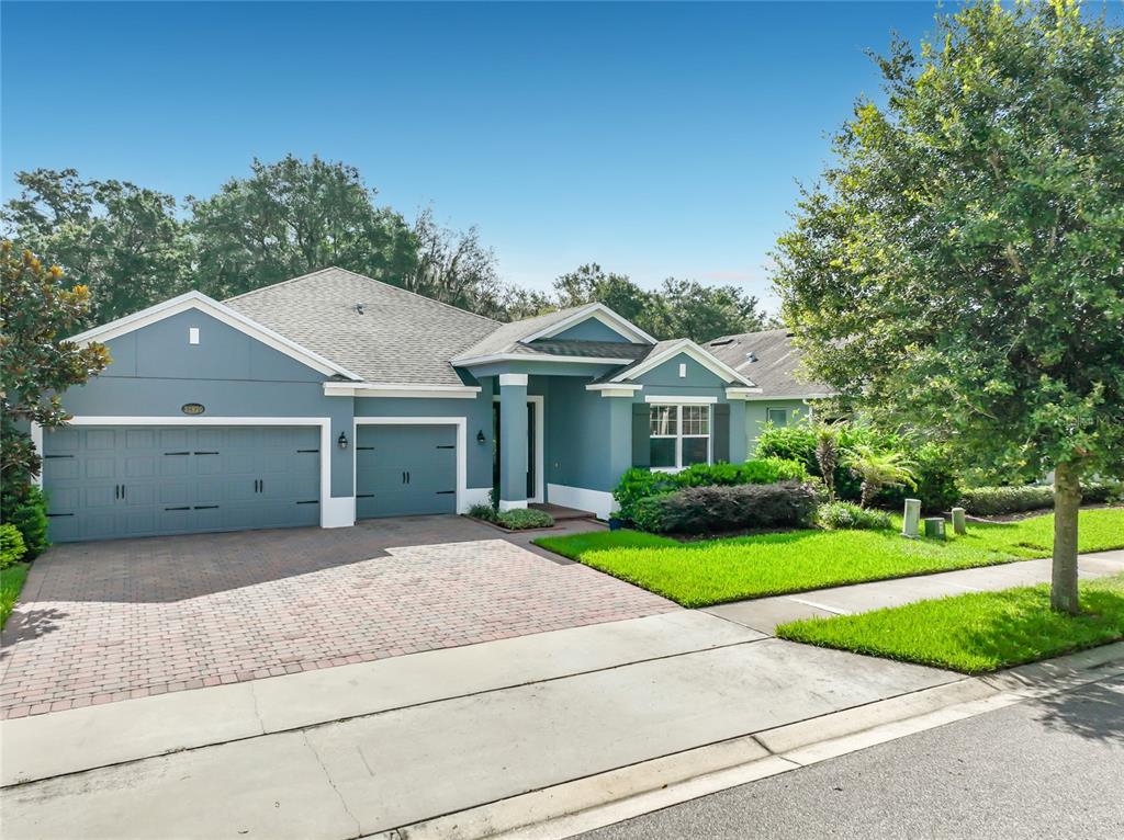 A blue single-story house with a three-car garage and a brick paver driveway — 31920 GEOFF WAY, SORRENTO, FL