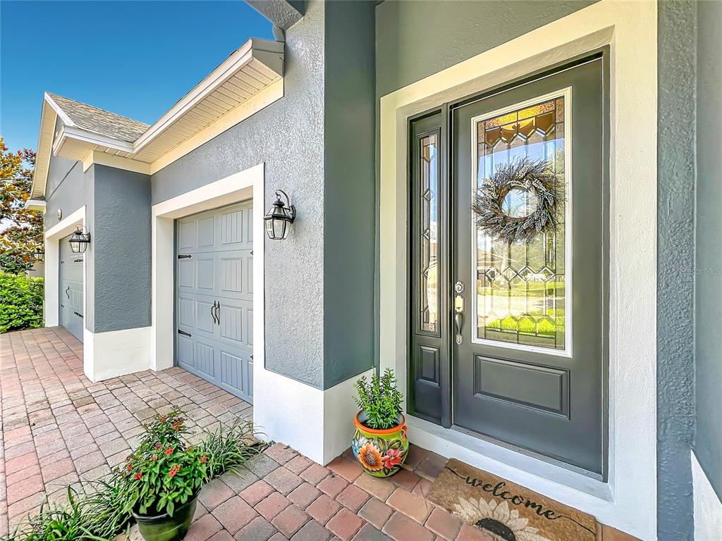 A blue house exterior features a dark front door, white trim, and a brick walkway — 31920 GEOFF WAY, SORRENTO, FL