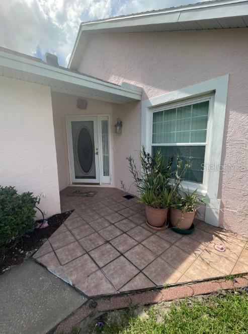 A light pink house exterior features a front door and a window with potted plants — 5399 NW 18TH STREET, OCALA, FL