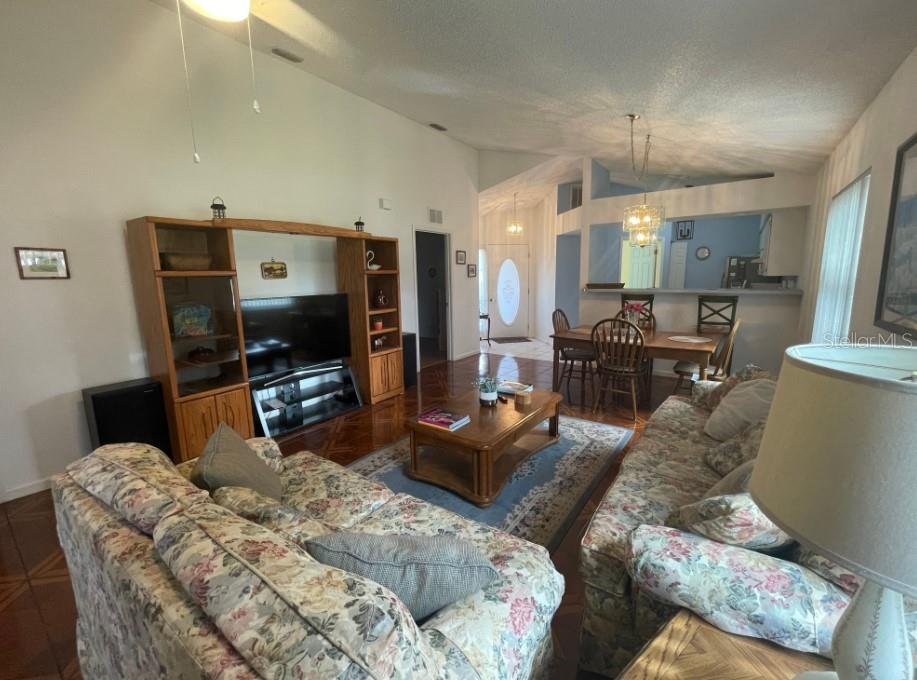A living room with floral sofas, a wooden entertainment center, and an adjacent dining area — 5399 NW 18TH STREET, OCALA, FL