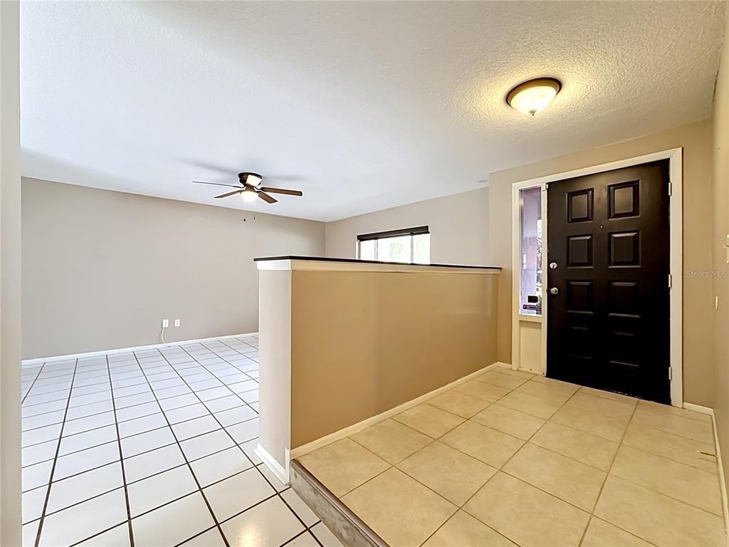An entryway with a black door and tiled floor leads to a sunken living area — 601 BRENTWOOD PLACE, BRANDON, FL