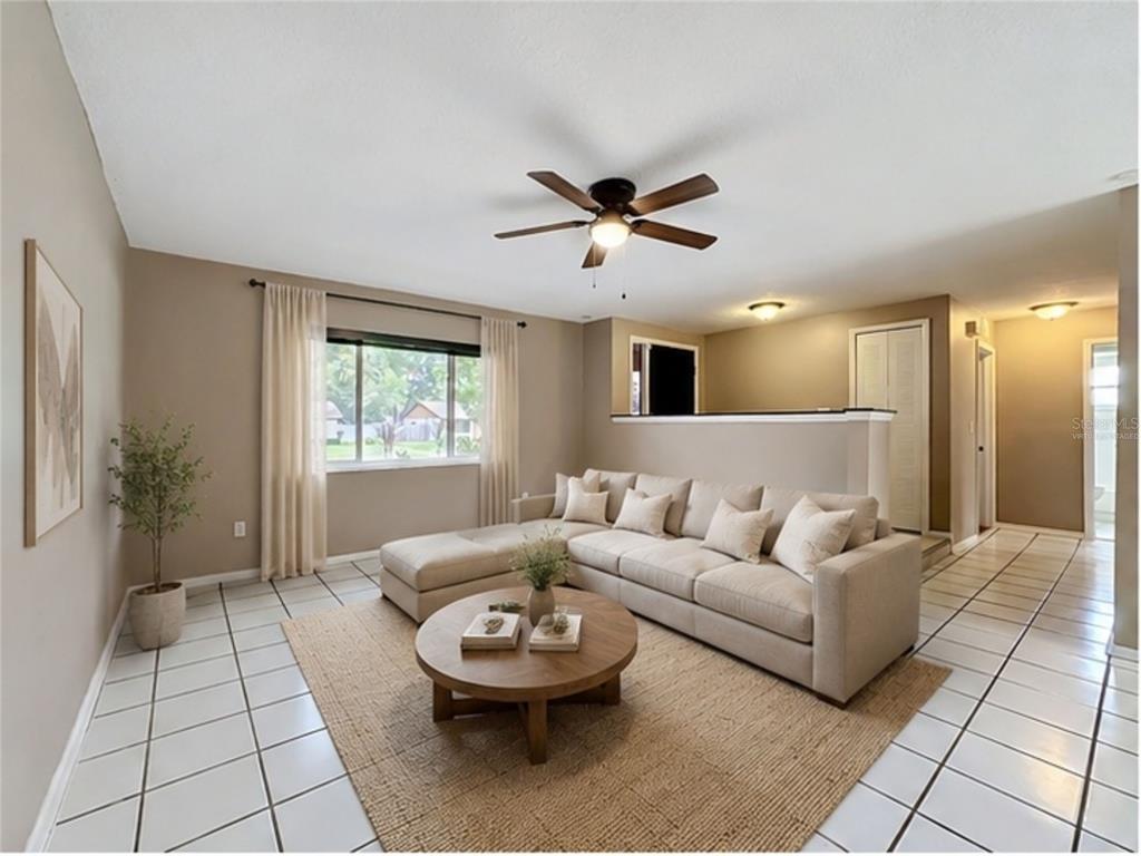A living room features a beige sectional sofa, a round wooden coffee table, and tile flooring — 601 BRENTWOOD PLACE, BRANDON, FL