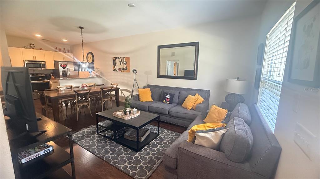 A living room and dining area feature gray sofas, a wooden table, and neutral walls — 2903 EDENSHIRE WAY UNIT 102, KISSIMMEE, FL