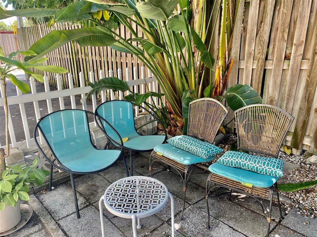 A patio area features four chairs and a small round table on a paved surface — 506 71ST AVENUE UNIT 4, ST PETE BEACH, FL