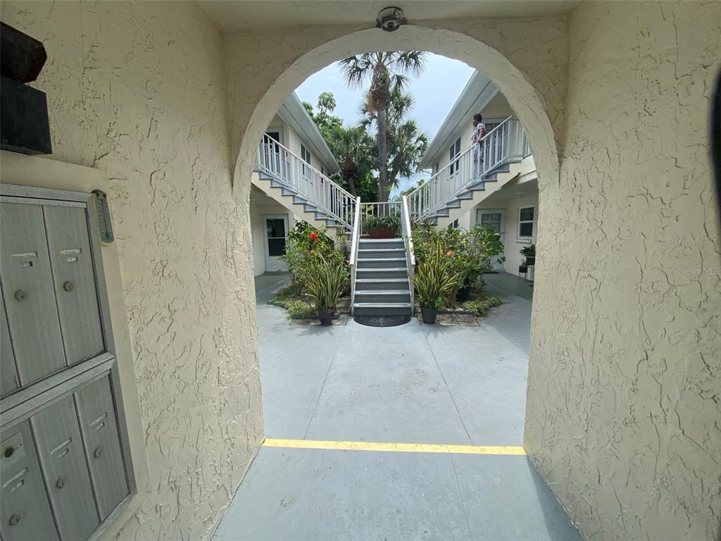 An arched entryway leads to a courtyard with a central staircase between two apartment buildings — 506 71ST AVENUE UNIT 4, ST PETE BEACH, FL